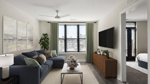 A living room with a blue couch and a flat screen TV mounted on the wall.