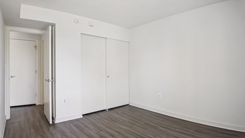 A room with a white door and two white closet doors.