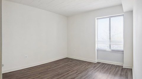 Empty room with wooden flooring and a window.