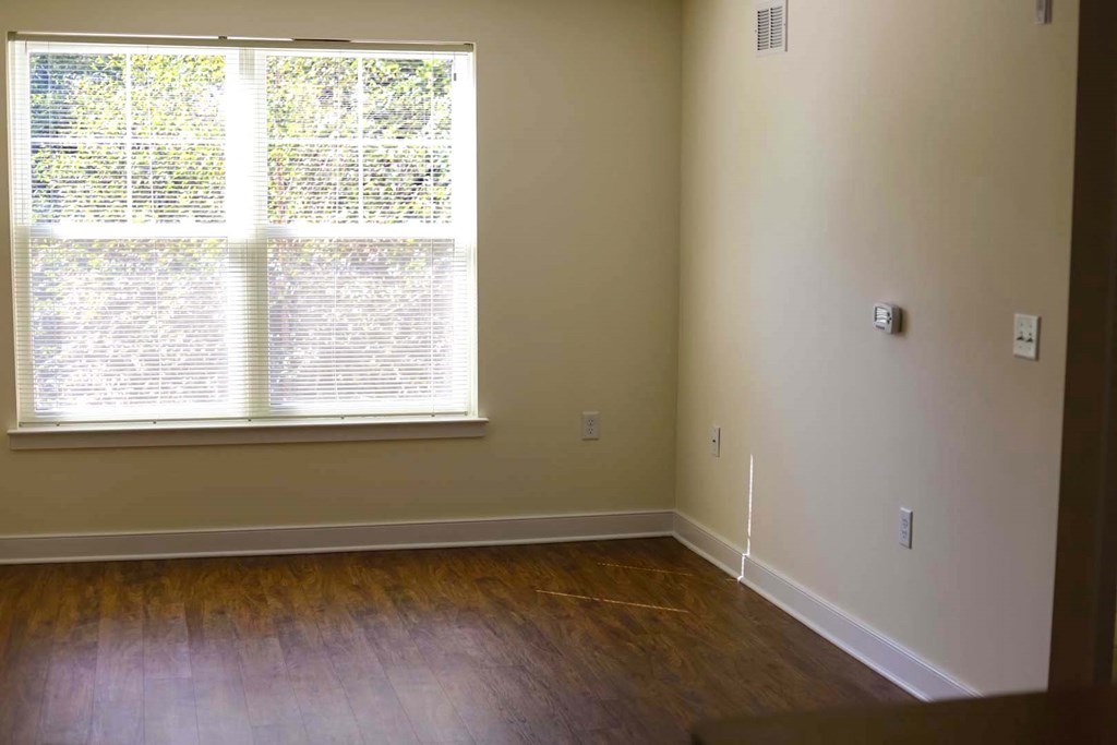 a living room with a large window and wooden floors