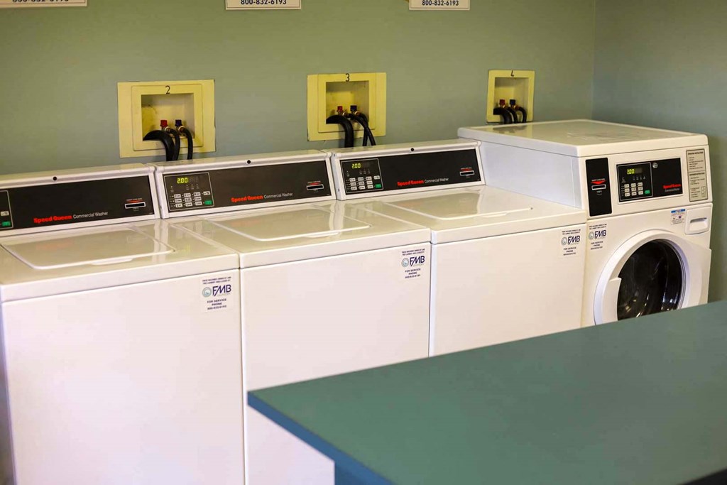 a row of washers and dryers in a laundry room
