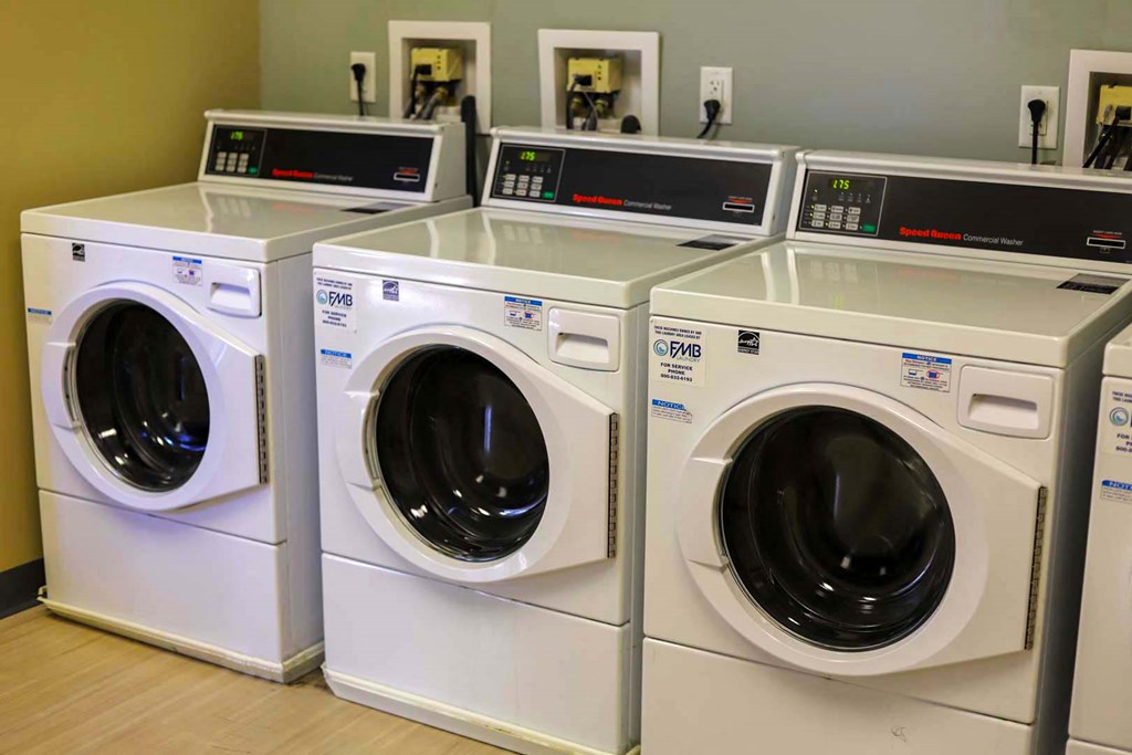 a row of washing machines and dryers in a laundry room
