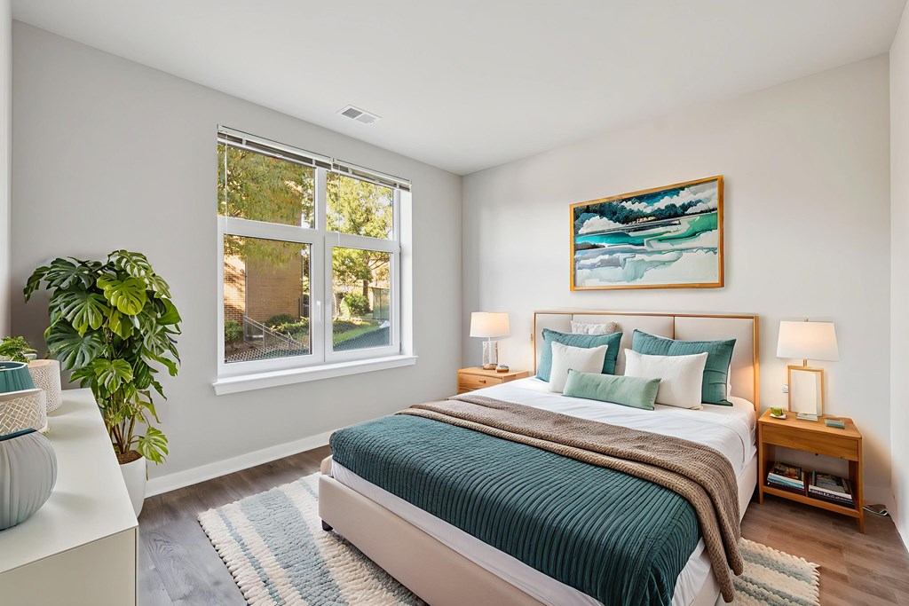 A bedroom with a bed, a potted plant, and a painting on the wall.