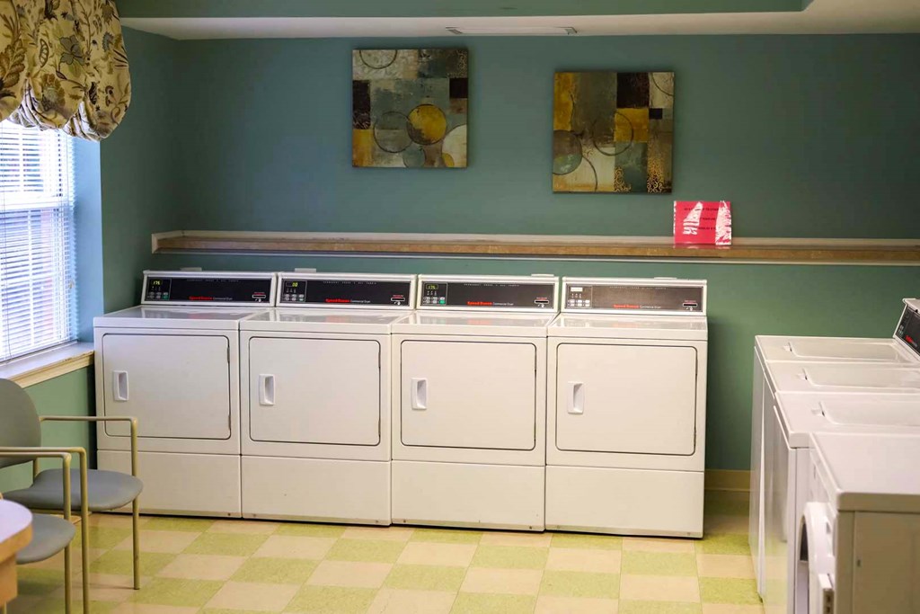 a laundry room with a row of washer and dryers