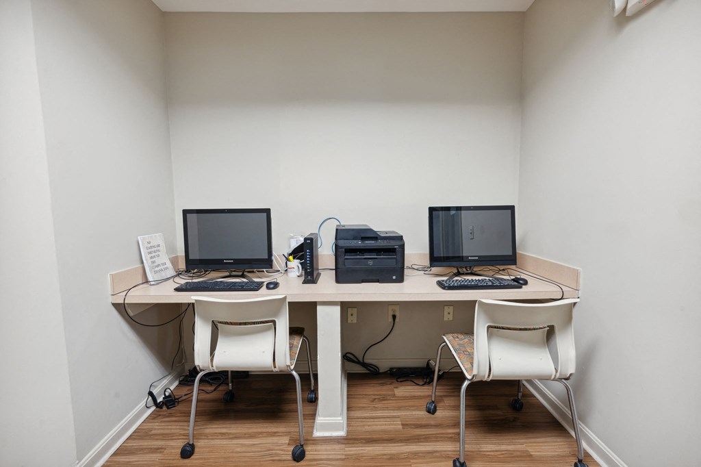 a desk with three computers and a printer on it