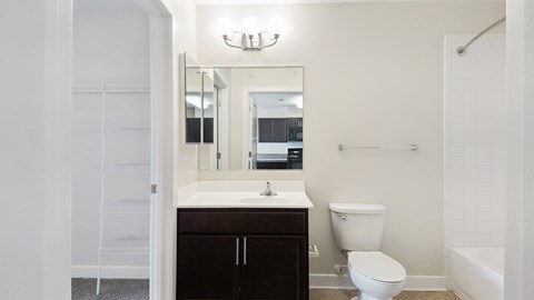 A white bathroom with a toilet, sink, and mirror.