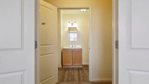 A hallway with a light on and a cabinet in the middle.