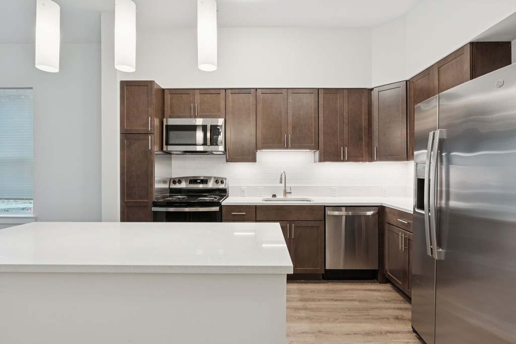 A modern kitchen with a white countertop and stainless steel appliances.