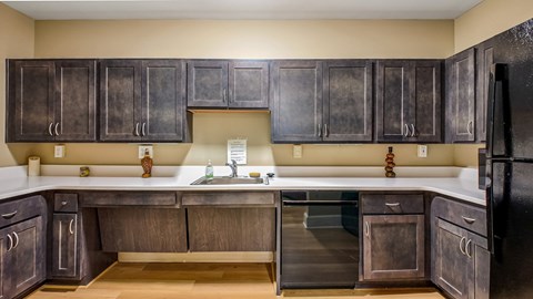 A kitchen with dark wood cabinets and a black refrigerator.