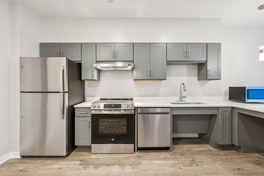 A modern kitchen with a refrigerator, oven, sink, and cabinets.