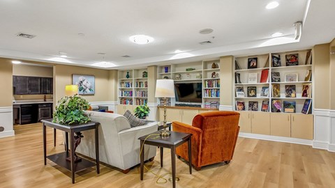 A living room with a fireplace, a couch, a chair, and a bookshelf filled with books.