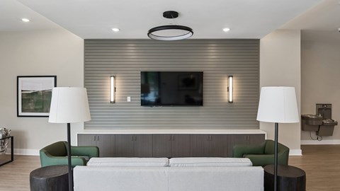 A modern living room with a grey sofa, green armchair, and a television mounted on the wall.