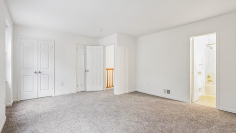 A spacious room with white walls and carpeted floor.