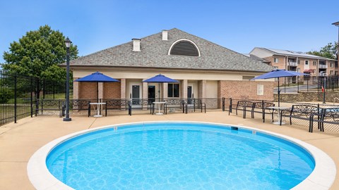 A swimming pool in front of a house with a black fence around it.