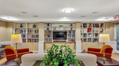 A living room with a large bookshelf filled with books and a flat screen TV mounted on the wall.