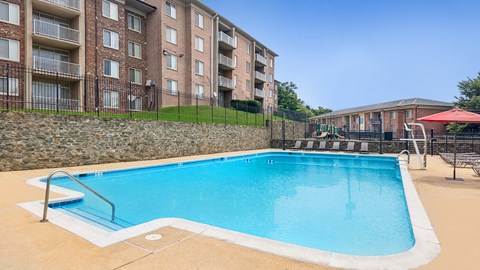 A swimming pool in front of a brick apartment building.