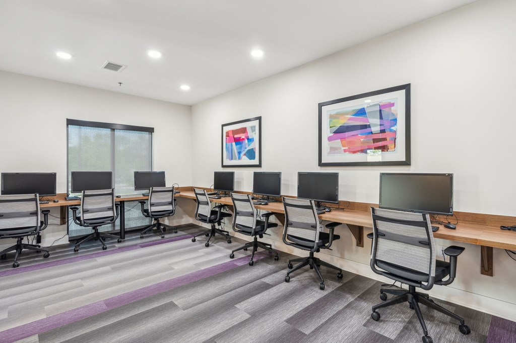 Legacy at Twin Rivers computer room with desks and chairs and paintings on the wall