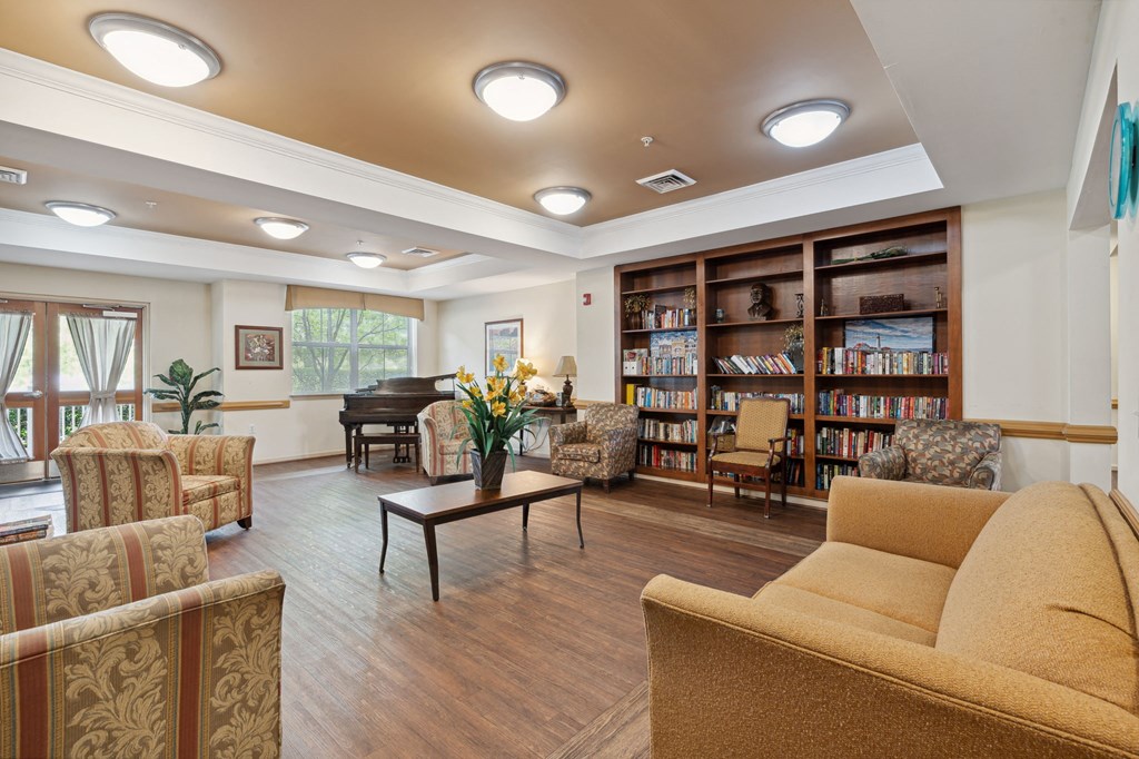 a room with couches chairs and a table with a vase of flowers and a piano