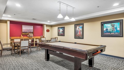 A room with a pool table and a dining table.