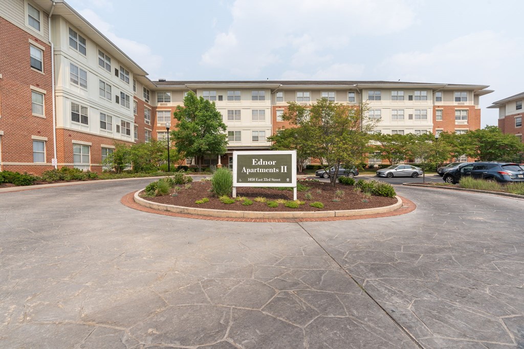 a circular driveway with a sign in the middle and a brick building in the background