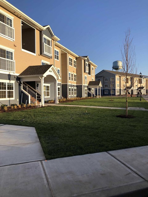 an exterior view of a row of apartments with grass and a sidewalk
