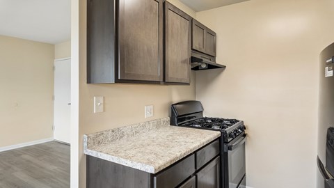 A kitchen with a black stove top oven and a counter top with a granite counter top.