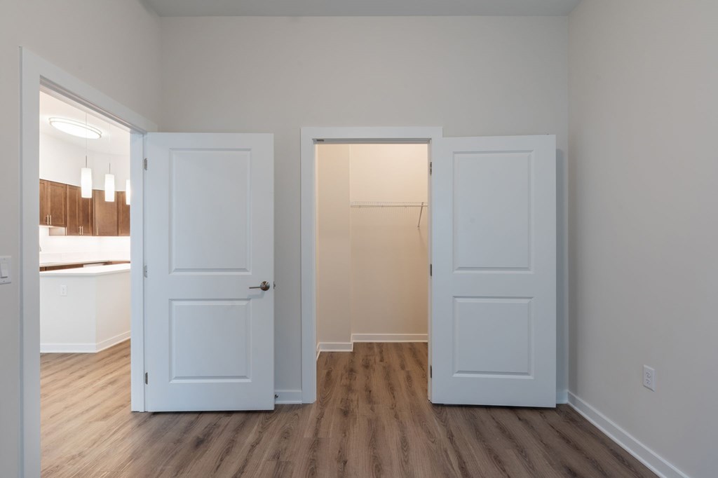Two white doors in a room with wood floors.