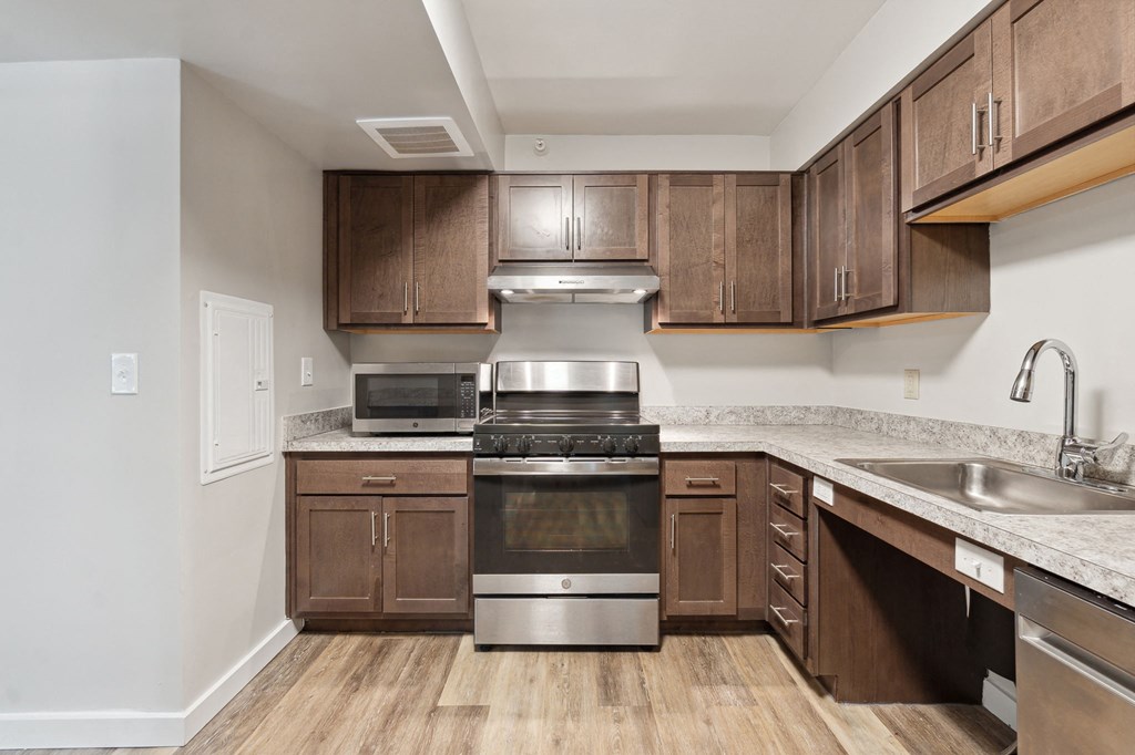 a kitchen with dark wood cabinets and stainless steel appliances