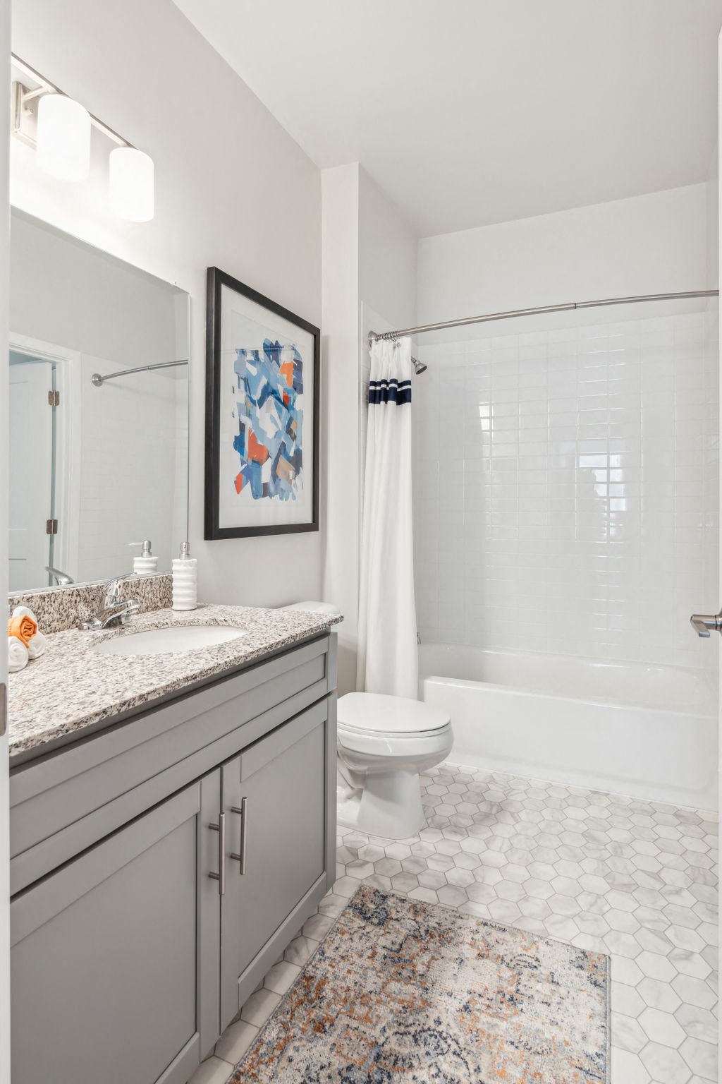 Bright bathroom with a shower and tub combo, toilet, sink, vanity and mirror.