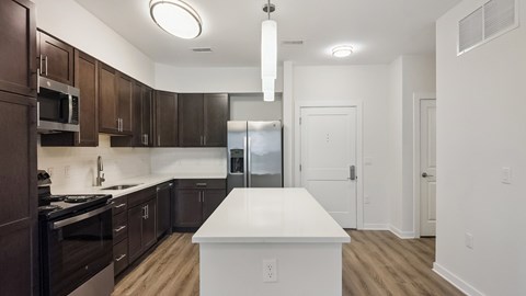 A kitchen with dark brown cabinets and a white island.