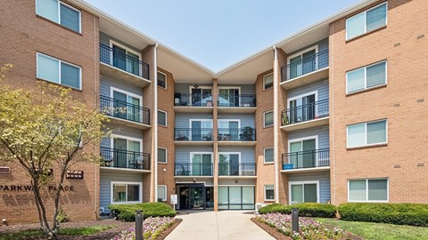 The image shows a multi-story apartment building named Parkway Place with a clear blue sky in the background.