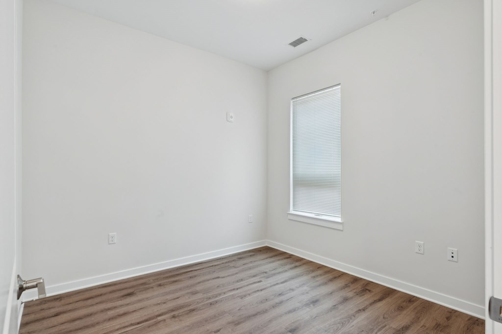 A room with a window and wooden flooring.