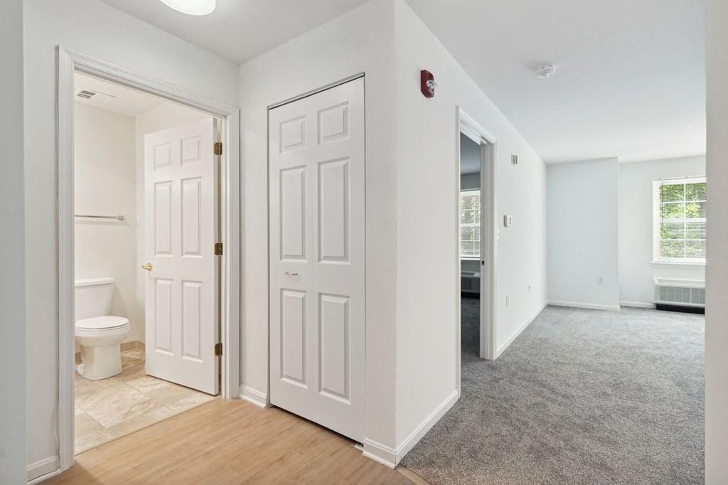 a bedroom with two doors and a bathroom in the background