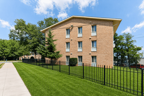 A brick building with a black fence in front.