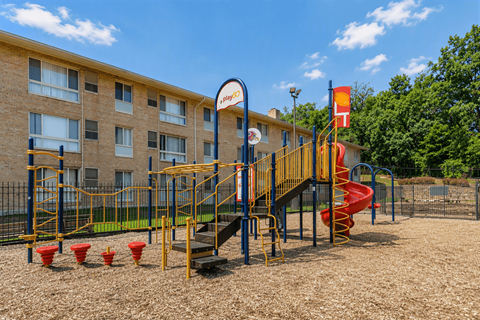 A playground with a yellow slide and red cones.
