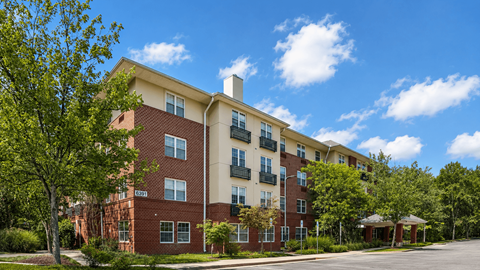 A red brick apartment building with a green tree in front.