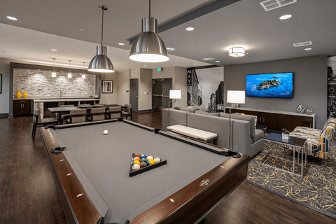 A billiard table is in the middle of a room with a TV on the wall.