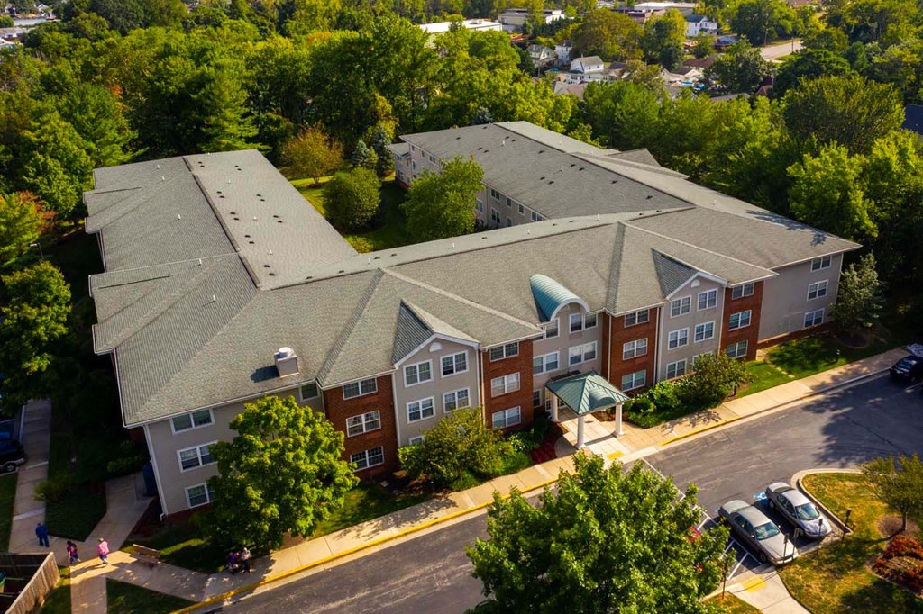 A large apartment complex with a green roof and a parking lot in front.