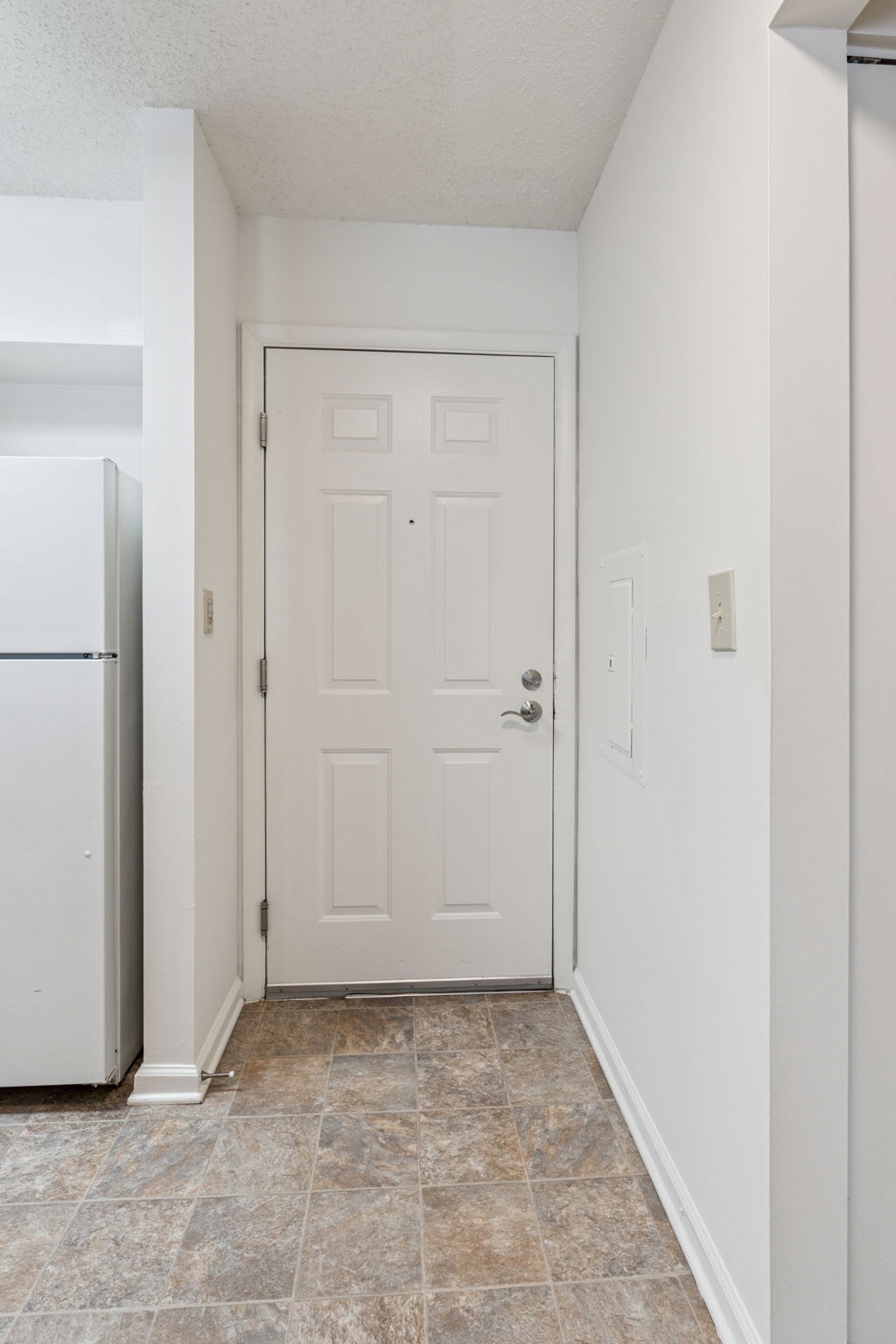 A white door is in a hallway with a tiled floor.