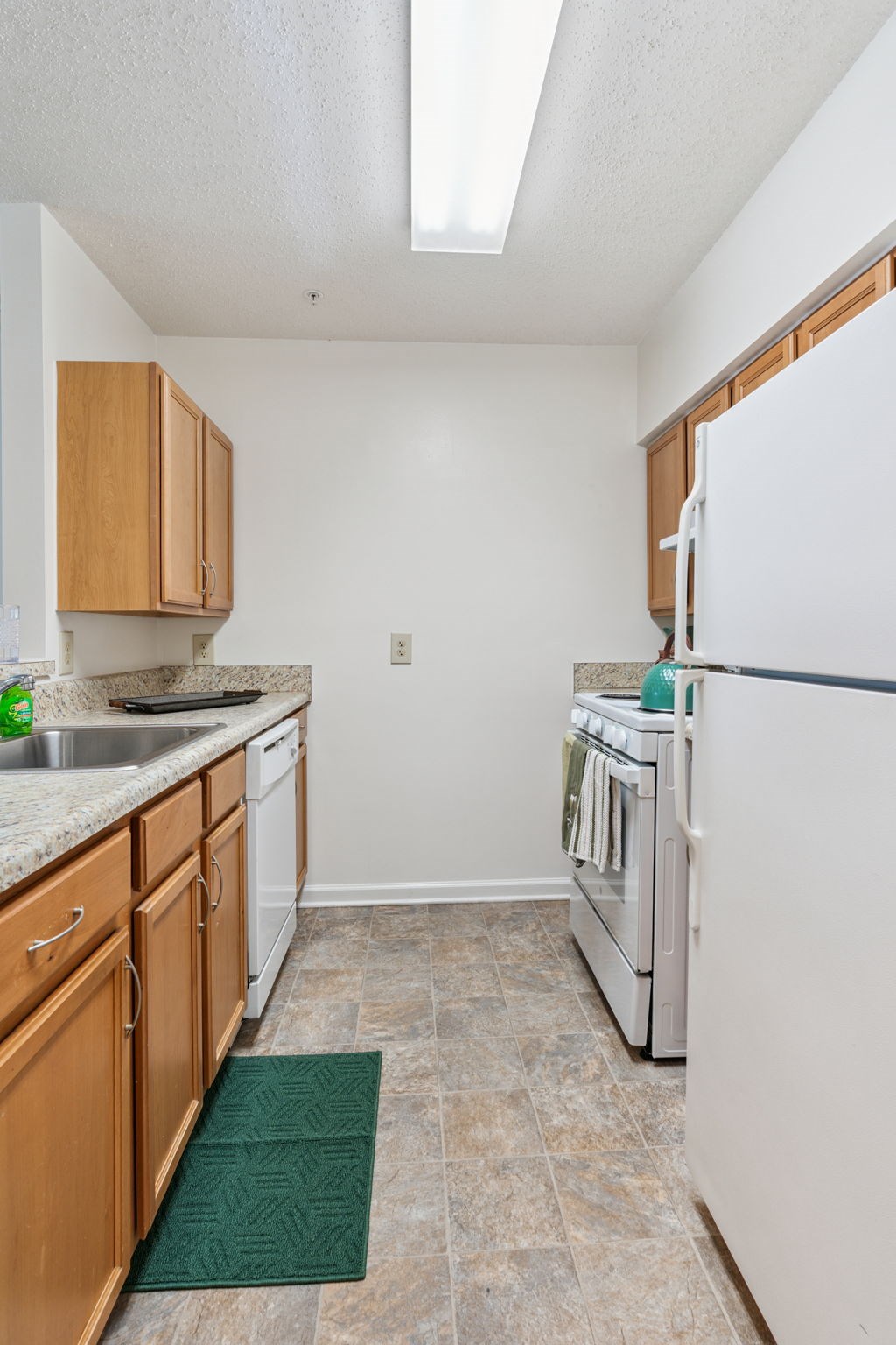 A kitchen with white appliances and wooden cabinets.