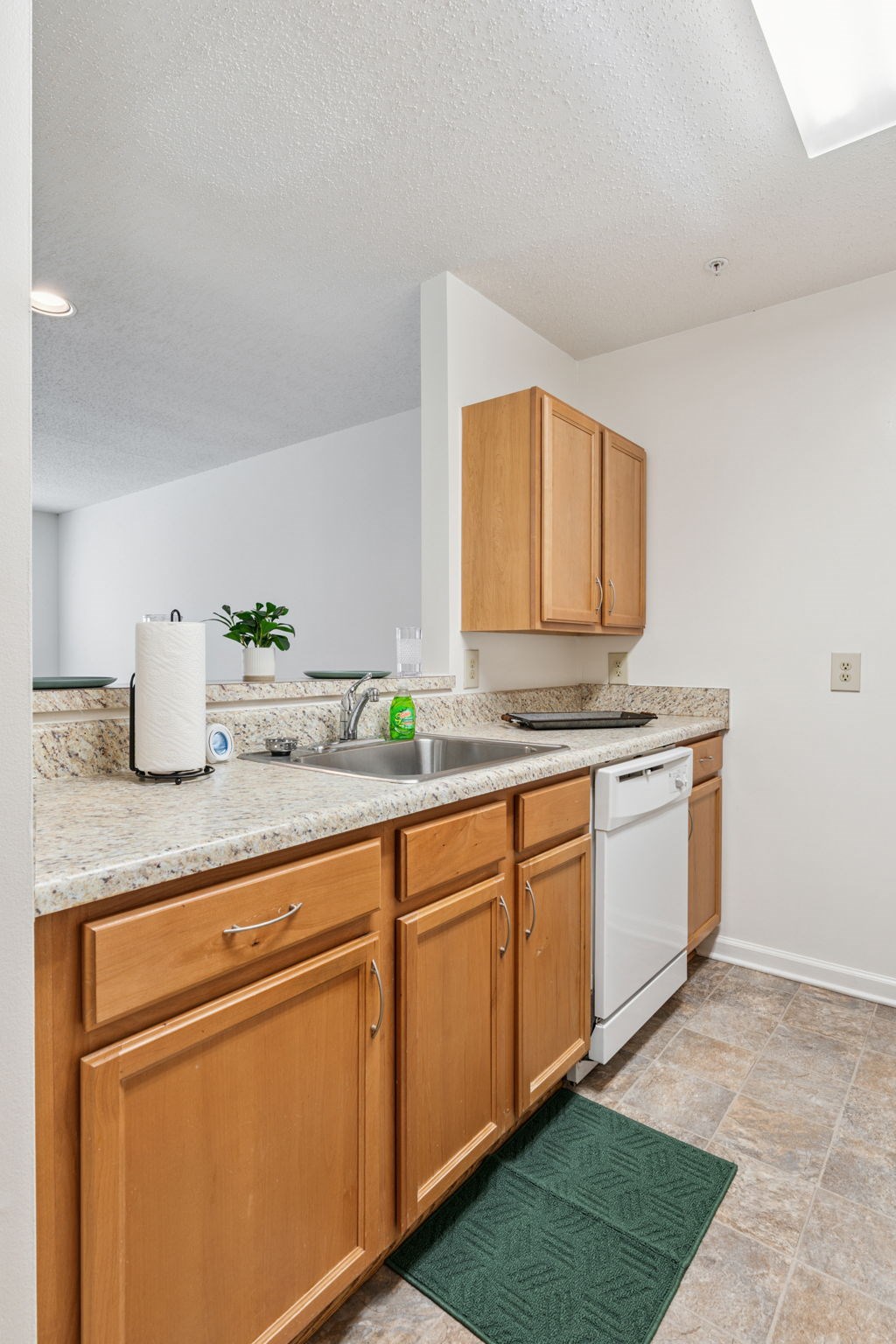 A kitchen with wooden cabinets and a green mat on the floor.
