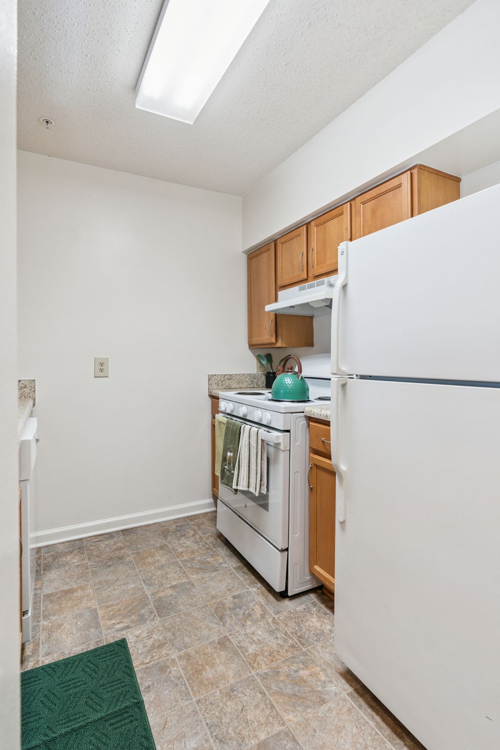 A kitchen with white appliances and wooden cabinets.