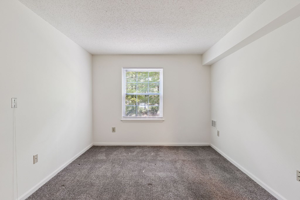 A room with a window and carpeted floor.