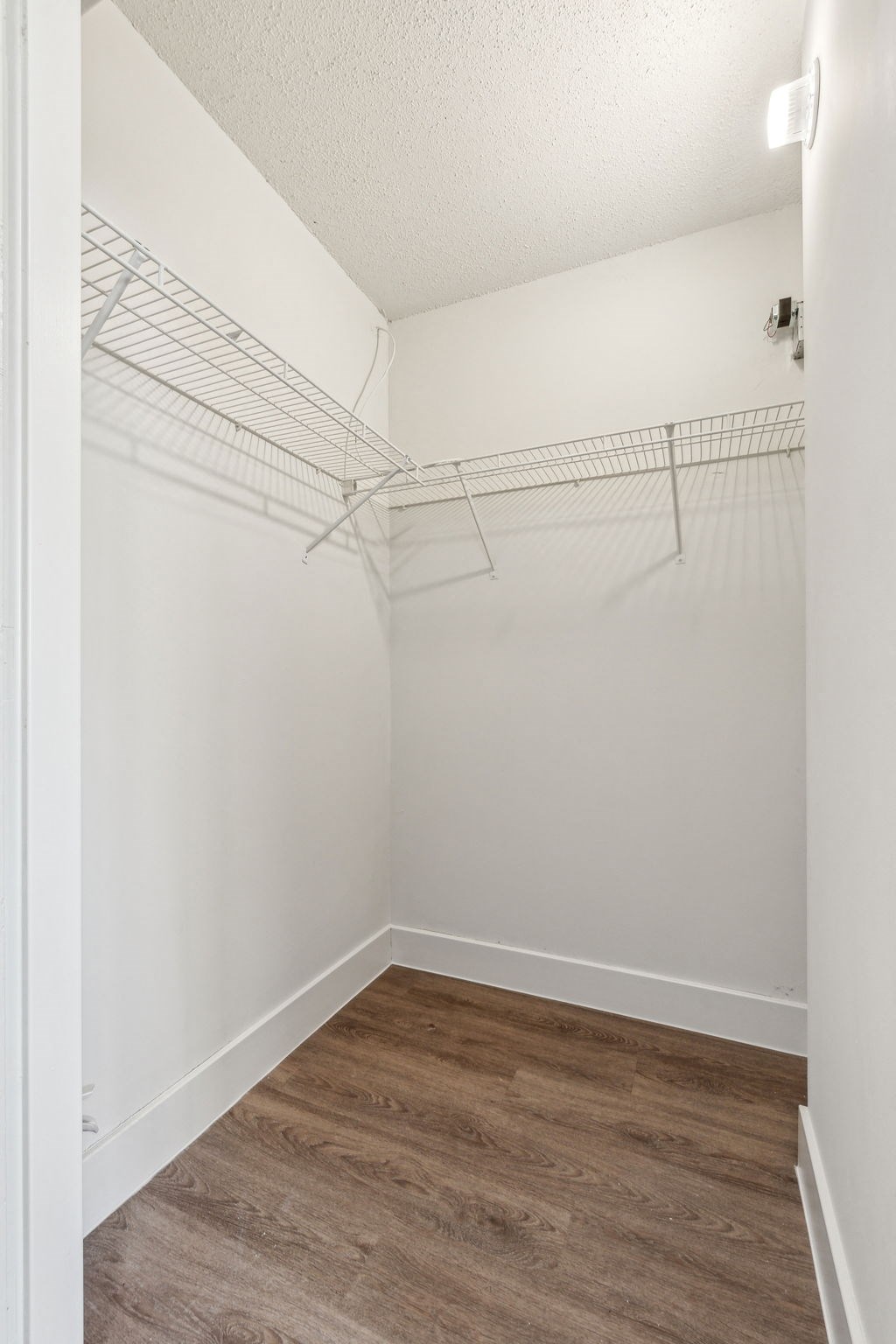A walk in closet with a white door and shelves.