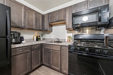 A kitchen with a black stove and wooden cabinets.
