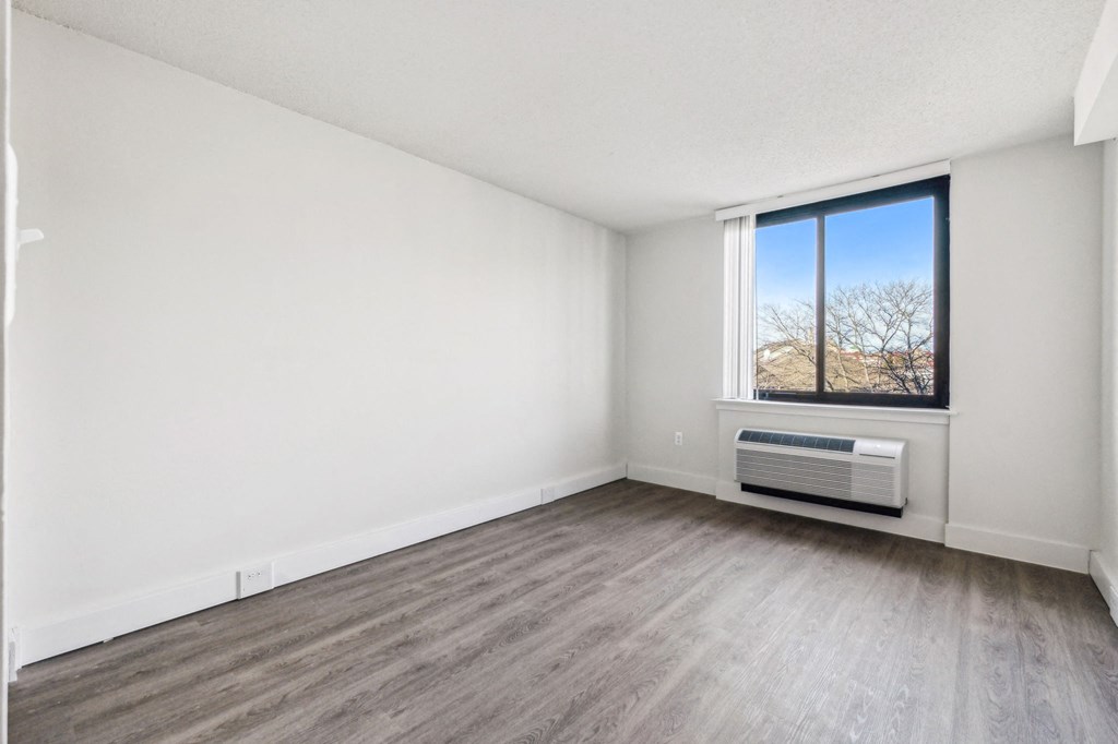 Bright, airy bedroom in a market-rate 2-bedroom apartment at Edgewood Commons 611 & Gardens, with generous closet space, luxury vinyl flooring, and plenty of natural light—ideal for comfort and rest.