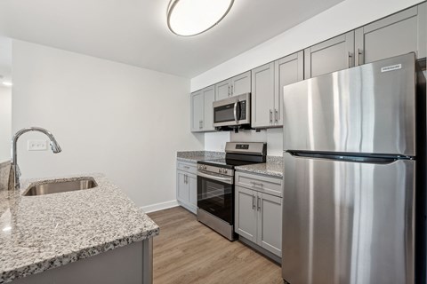 A modern kitchen with a stainless steel refrigerator and a granite countertop.