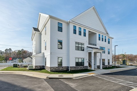 A white building with a parking lot in front.