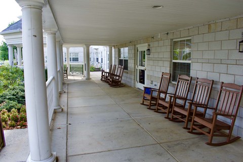 A spacious porch with white columns and rocking chairs.