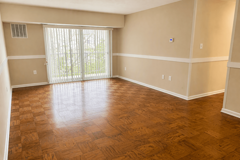 A room with wooden flooring and a sliding glass door.